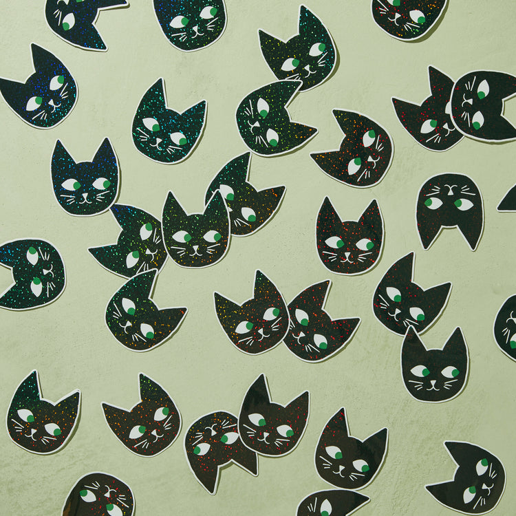 Glitter Cat Head Sticker showing multiple black cat faces with green eyes and glitter details on light background