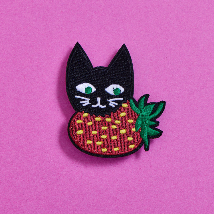 Strawberry Cat Patch showing a black cat holding a red strawberry with green leaves on a pink background
